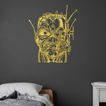A gold vinyl wall decal of Eddie Cyborg applied to a dark gray bedroom wall above a bed.