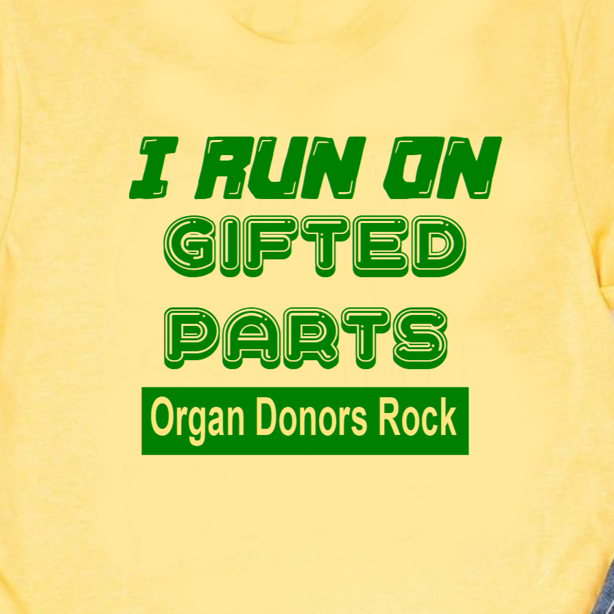 “Organ recipient ‘I Run On Gifted Parts’ tee, yellow shirt with green vinyl text, flat lay”