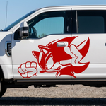 A white Ford pickup truck parked outdoors on a gravel surface under a clear blue sky, featuring a large red Sonic the Hedgehog graphic decal on the side door.