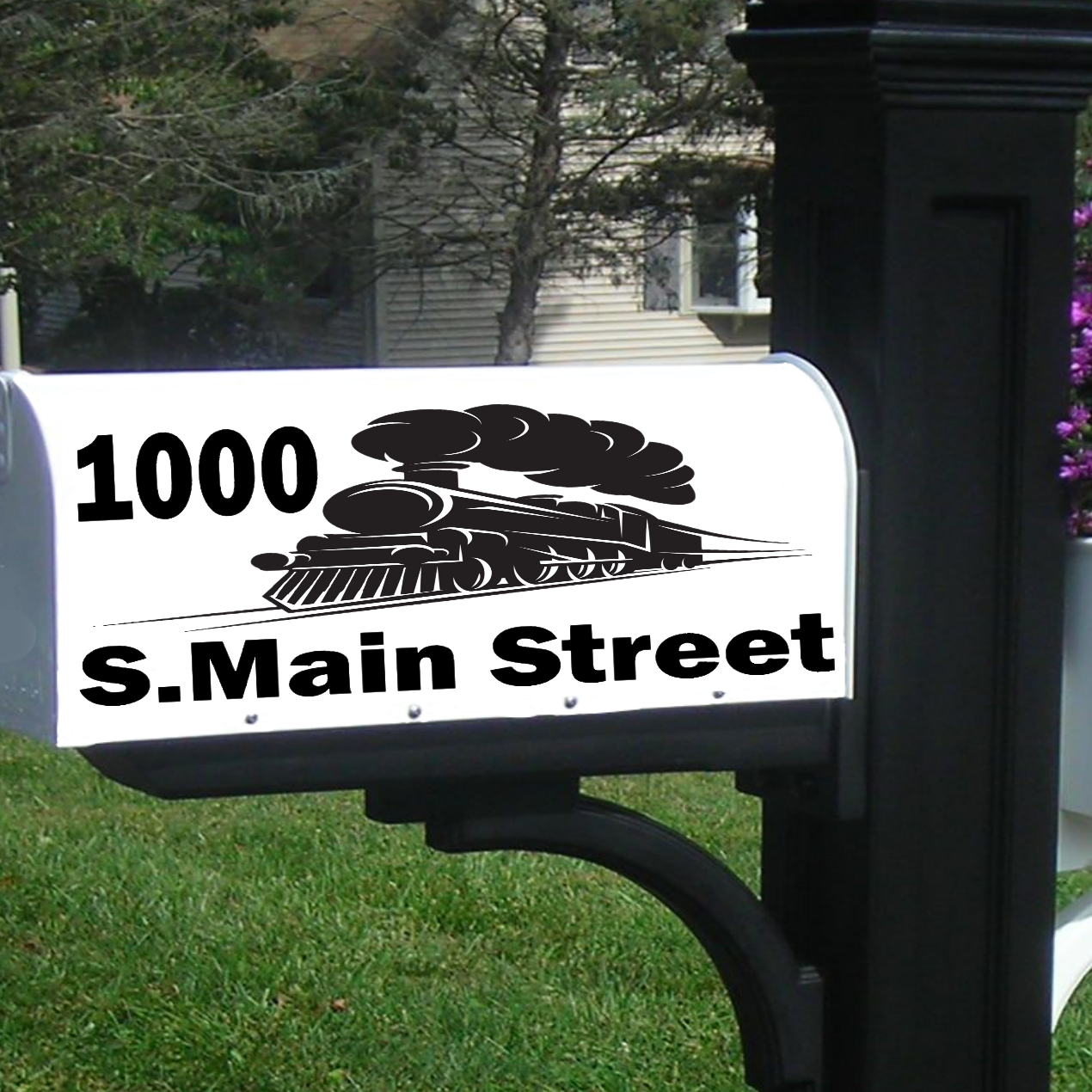 Black mailbox post with white mailbox displaying '1000 S. Main Street' in a garden setting.