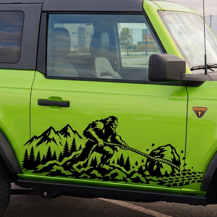 A bright lime green Ford Bronco with a black roof and a black mountain graphic decal on the side, parked in an outdoor paved lot under an overcast sky.