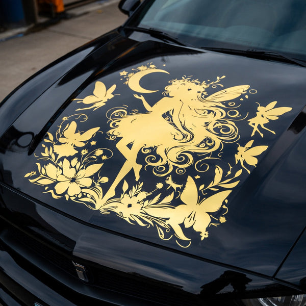 Gold fairy silhouette vinyl decal with moon, butterflies, and flowers on a black car hood