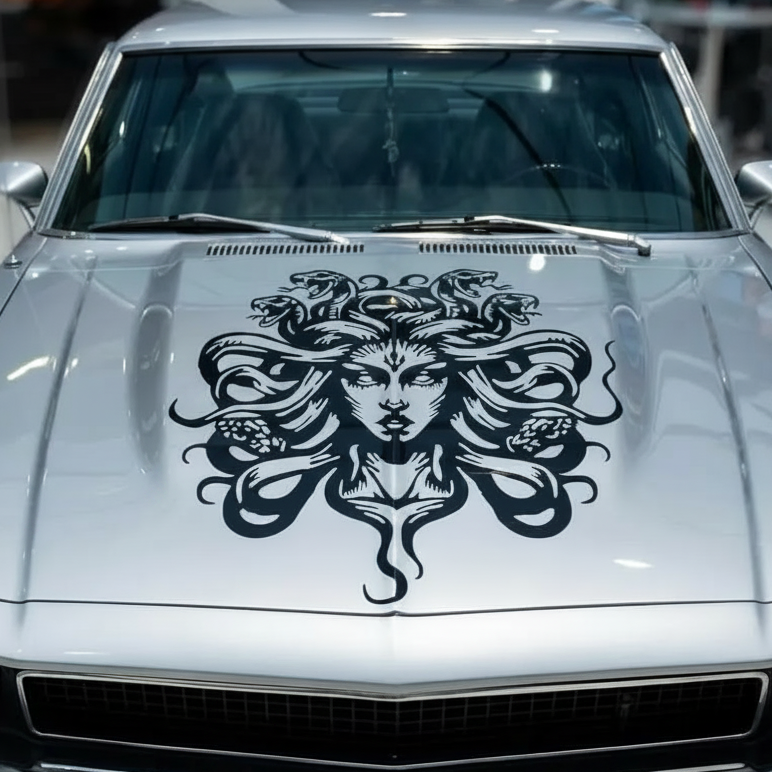Silver  car with a black Medusa hood design in a showroom setting