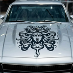Silver  car with a black Medusa hood design in a showroom setting