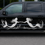 A black Ford F-150 pickup truck parked outdoors in front of a modern glass building, featuring a large white mermaid and merman graphic decal running along the side of the vehicle.