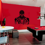 A modern gaming room featuring a red wall with a large black Spider-Man graphic, a red pool table, a small round table with chrome stools, and a garage door in the background.