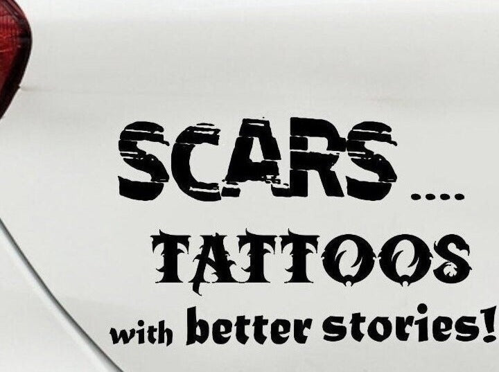 “Black ‘Scars — Tattoos with Better Stories’ car decal on light tailgate, 11‑inch width, high‑contrast lettering”